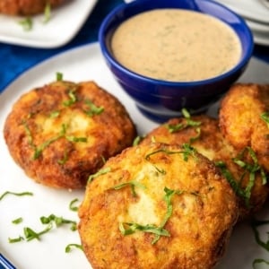 Closeup of three potato fish cakes on a plate.