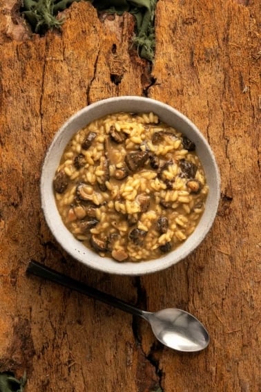 A bowl of mushroom risotto on a wooden table.