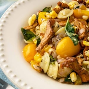 Close up of a bowl of chanterelle pasta, showing the mushrooms and the cherry tomatoes.