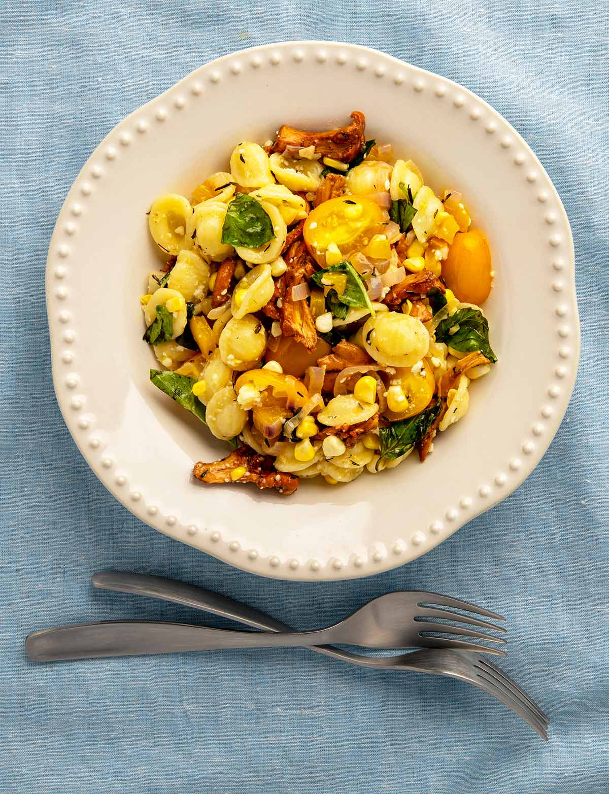 A plate of chanterelle pasta with cherry tomatoes, sweet corn, basil and golden bell pepper. 