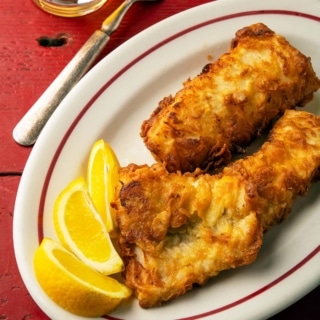 Three pieces of fried walleye with lemon wedges.