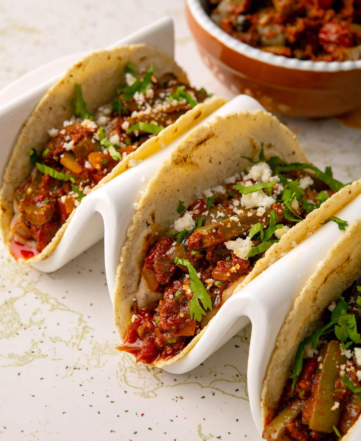 Close up of three tacos filled with carne con nopales on a taco holder. 