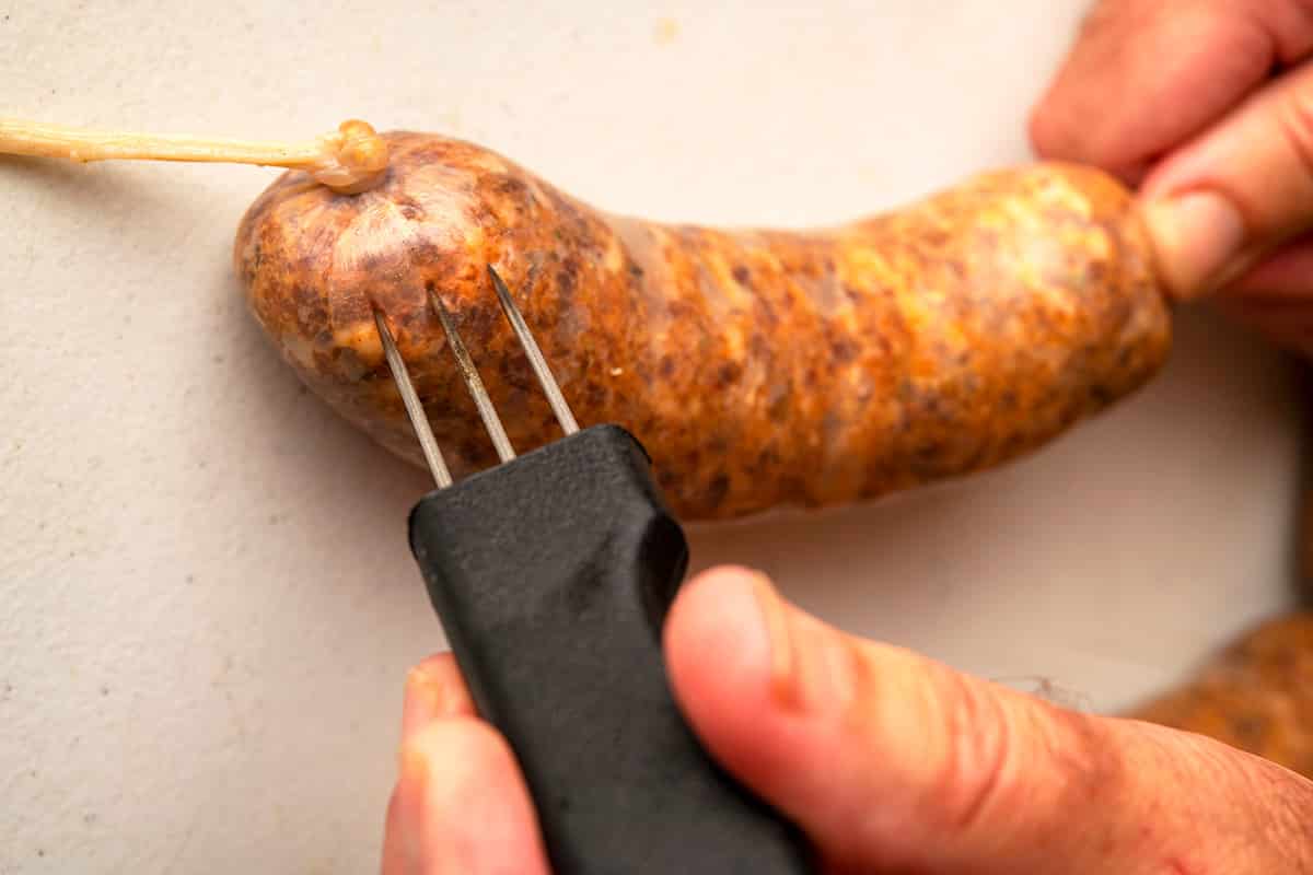 Piercing a sausage casing to remove air pockets.