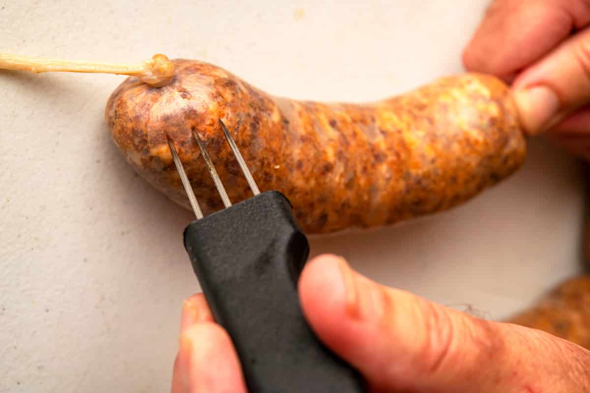 Piercing a sausage casing to remove air pockets. 