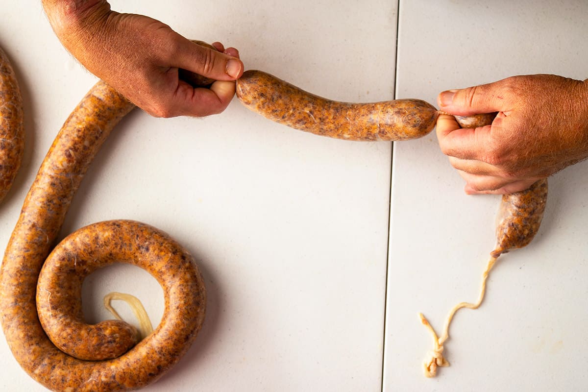 Spinning a link of sausage to tighten it.