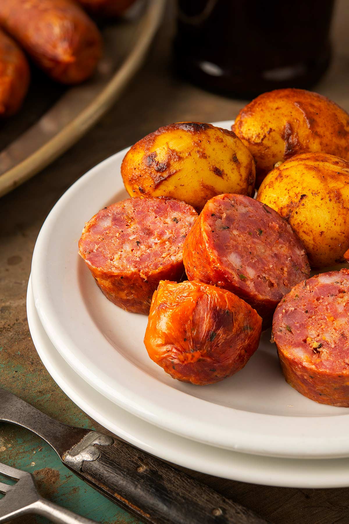 Texas hot links sliced on a plate with chile-roasted potatoes. 