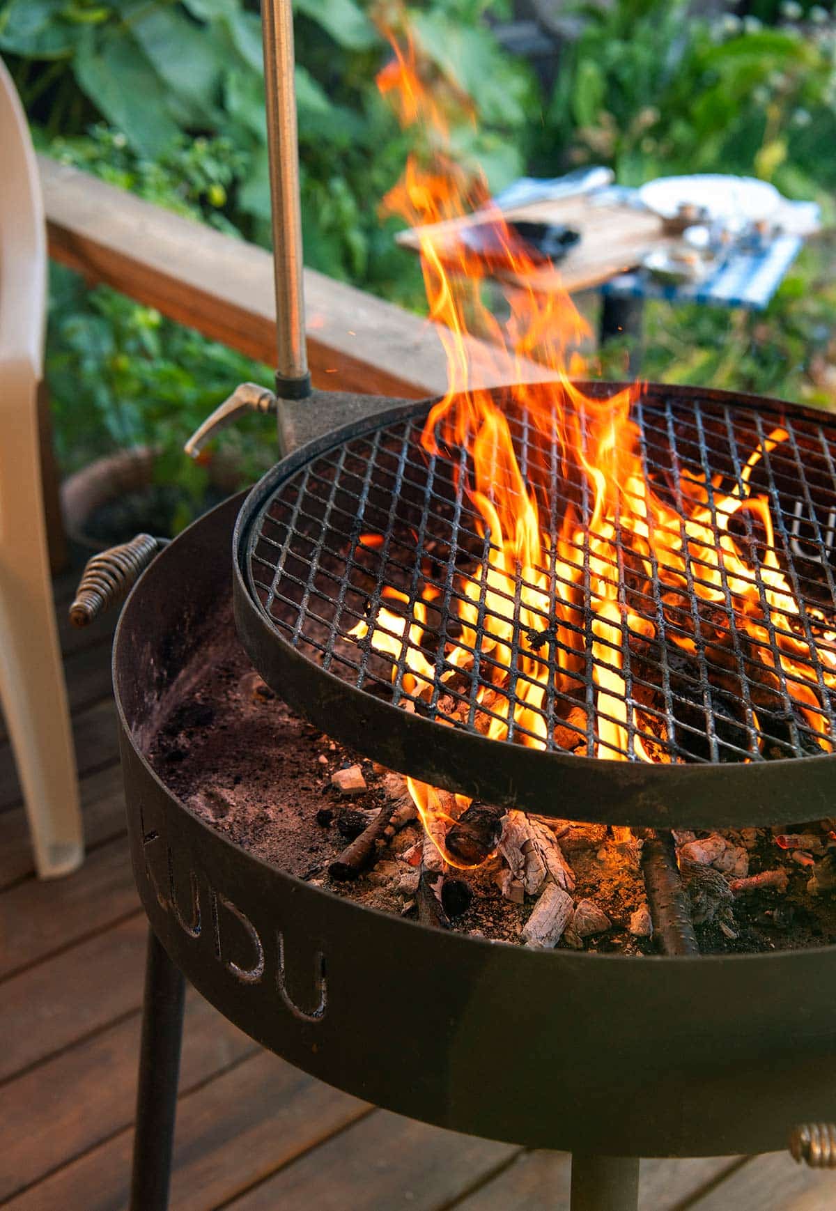 Flames leaping up on a charcoal grill, heating the grates. 