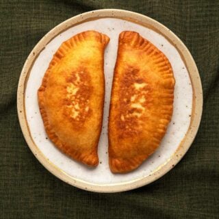 Two lihapiirakka, Finnish meat pies, on a plate.