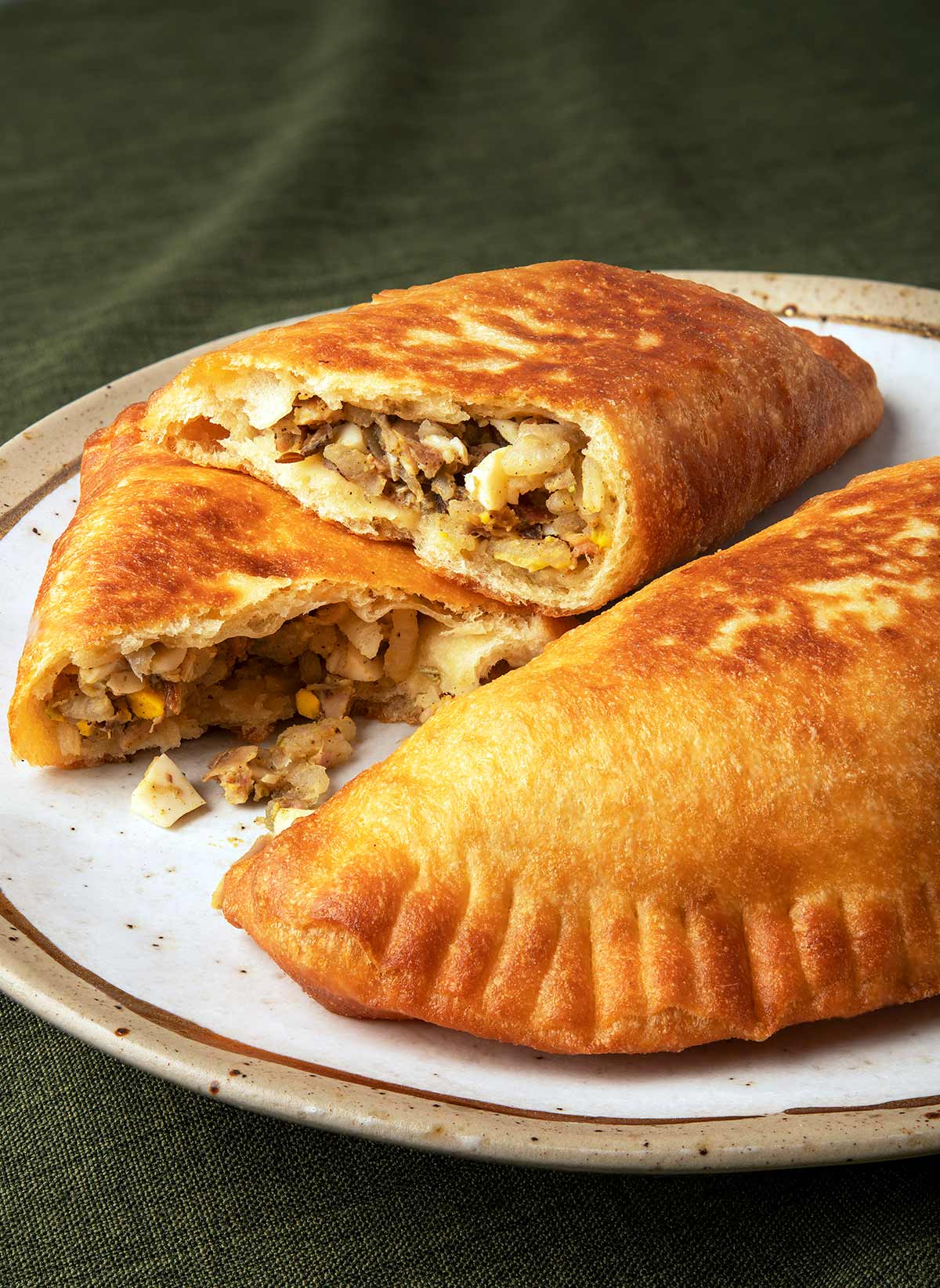 Two lihapiirakka, Finnish meat pies, on a plate with one broken open. 