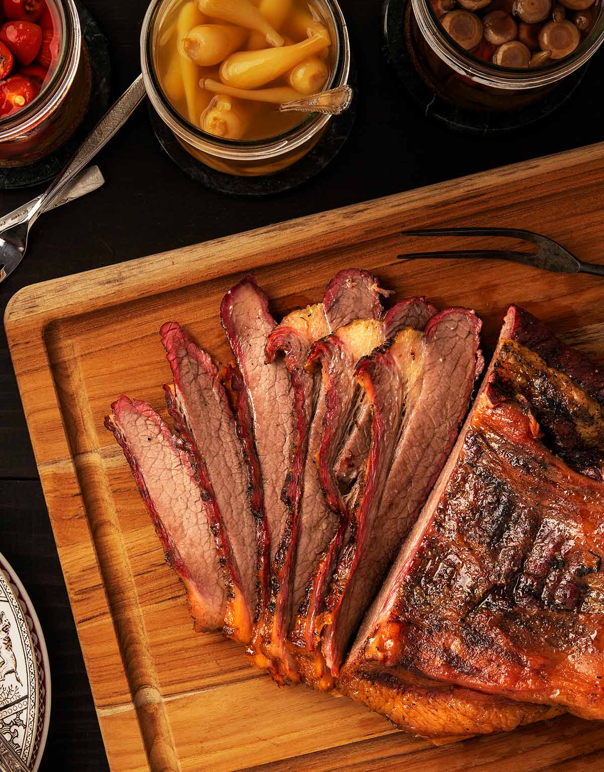 Slices of bison brisket, with an array of pickles alongside them. 