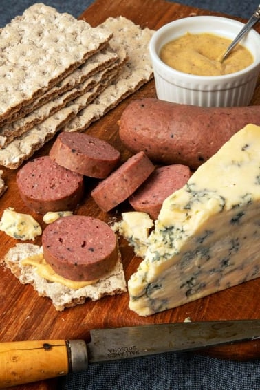 Slices of braunschweiger sausage with crackers, mustard and blue cheese.
