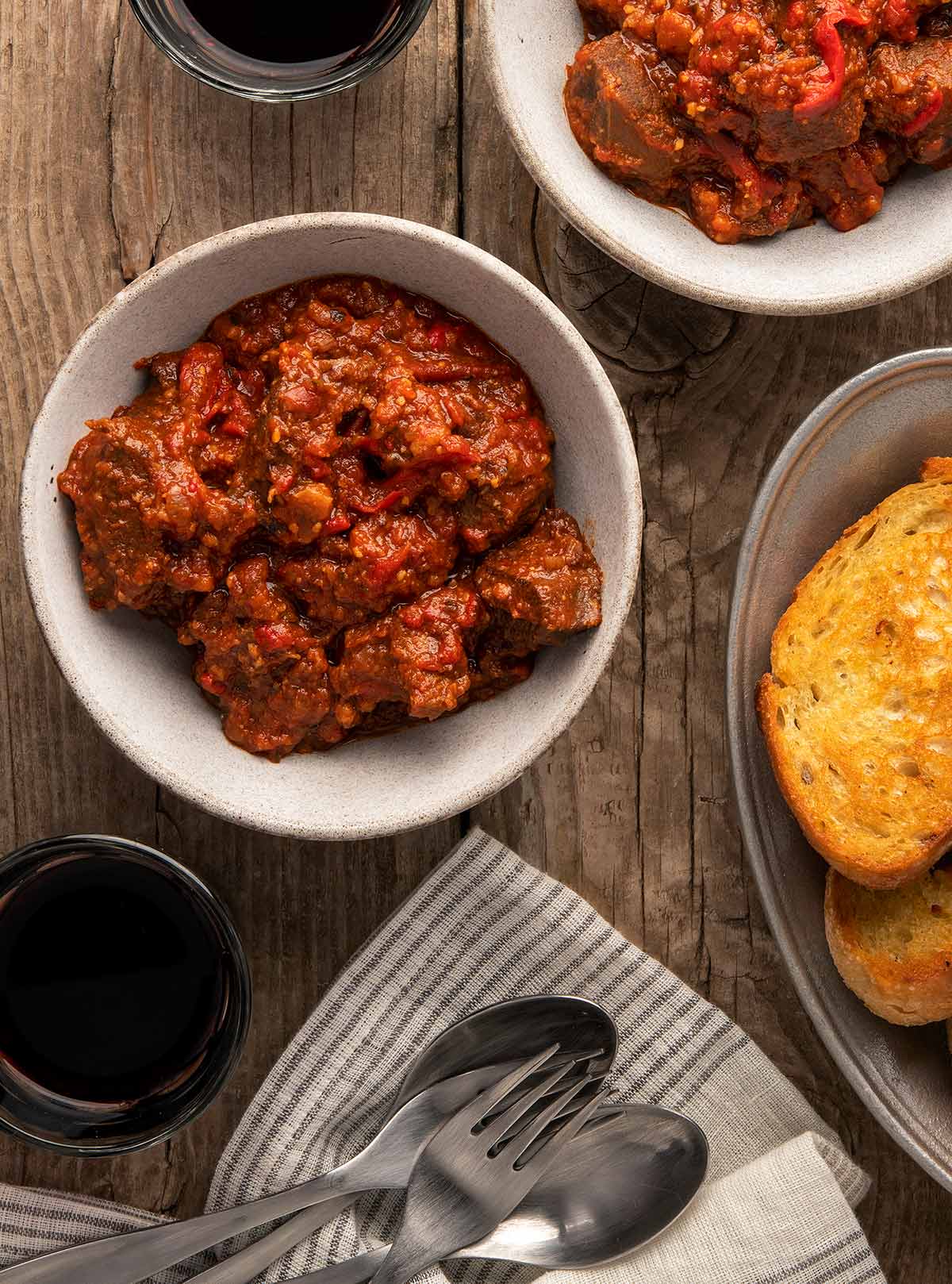 Two bowls of Spanish caldereta with wine and bread. 