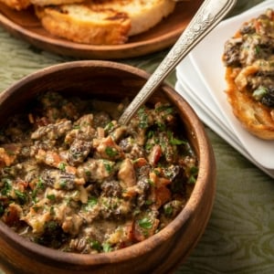 Creamy mushrooms in a bowl with toast alongside.