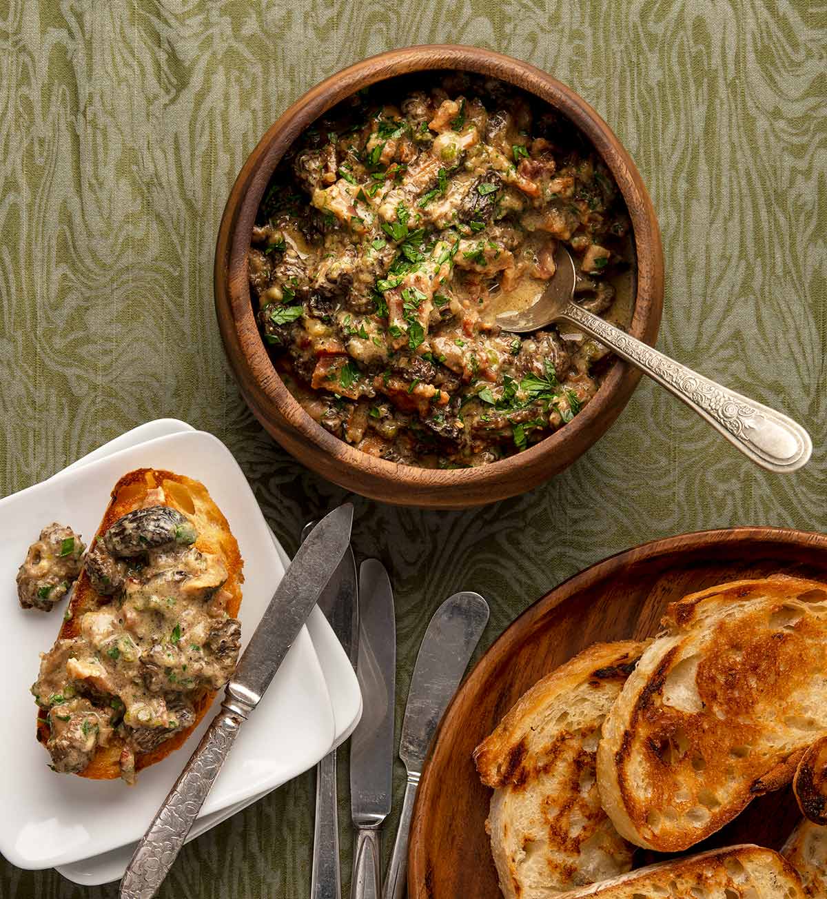 Creamy mushrooms on toast, with extra toast and a pot of the mushrooms nearby. 