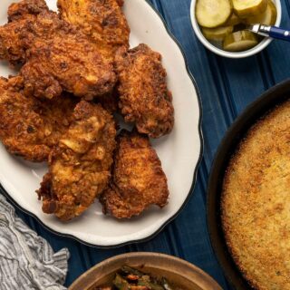 A platter of fried pheasant with pickles, cornbread and green beans.