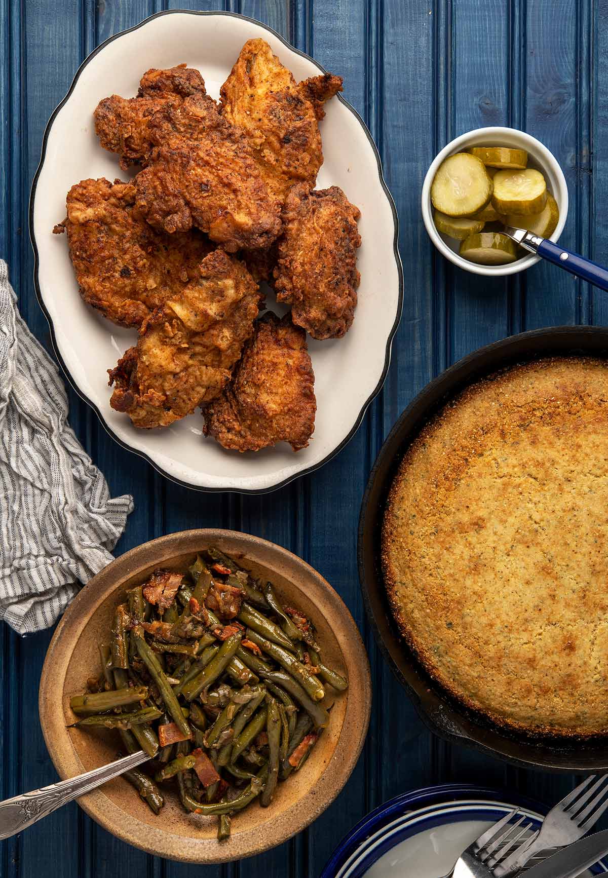 A platter of fried pheasant with all the fixins - green beans with bacon, pickles and cornbread. 