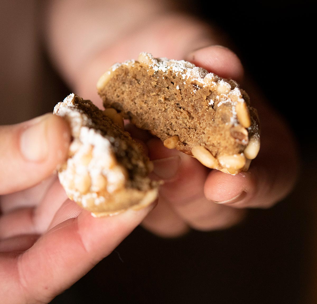 Breaking open a pine nut cookie made with acorn paste, showing the dark interior. 