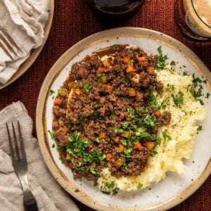 A plate of Scottish mince and tatties with a glass of beer.