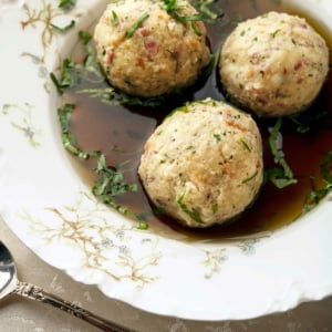 Close up of three canederli dumplings in broth.