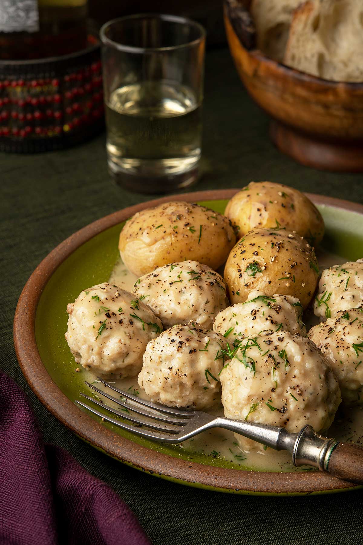 Close up of pike balls with dill cream sauce, served with potatoes. 