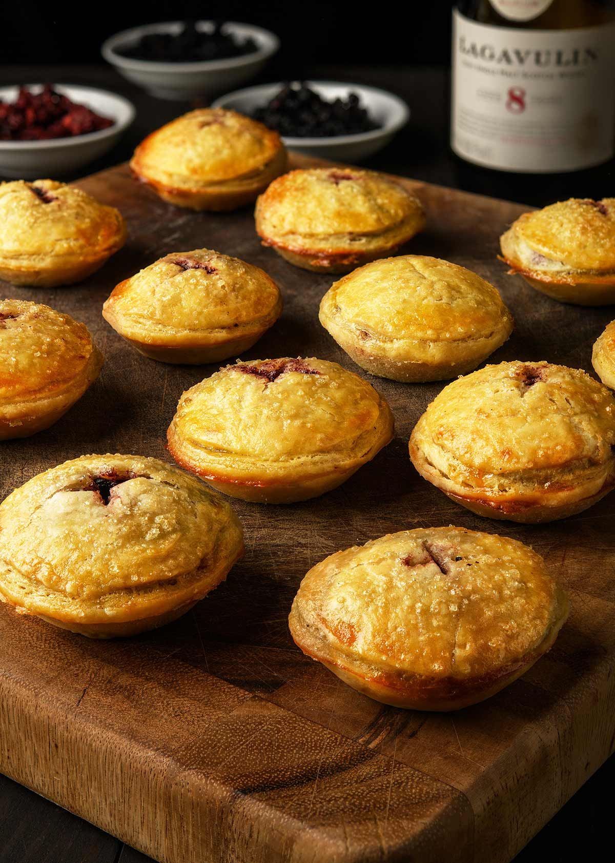 A dozen venison mincemeat pies on a cutting board. 