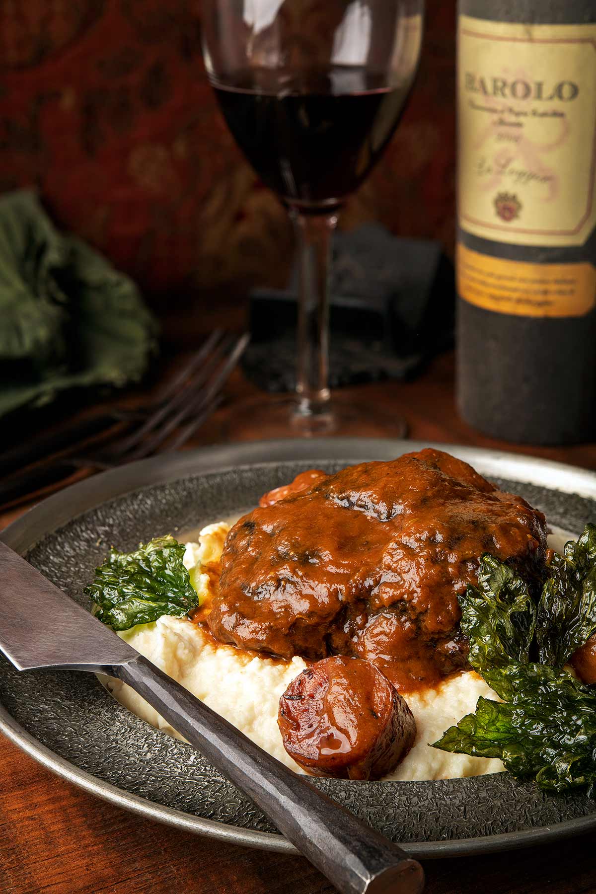 Braised beef cheeks with a red wine sauce over mashed potatoes on a plate. 