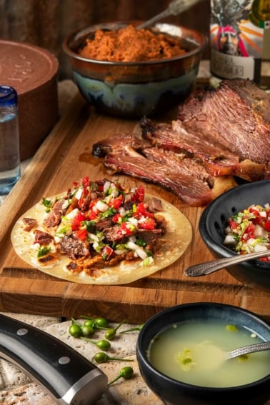 Brisket tacos with all the fixins on a cutting board.