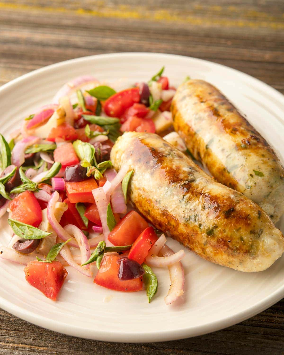 Close up of fish sausages on a plate with a summer salad. 