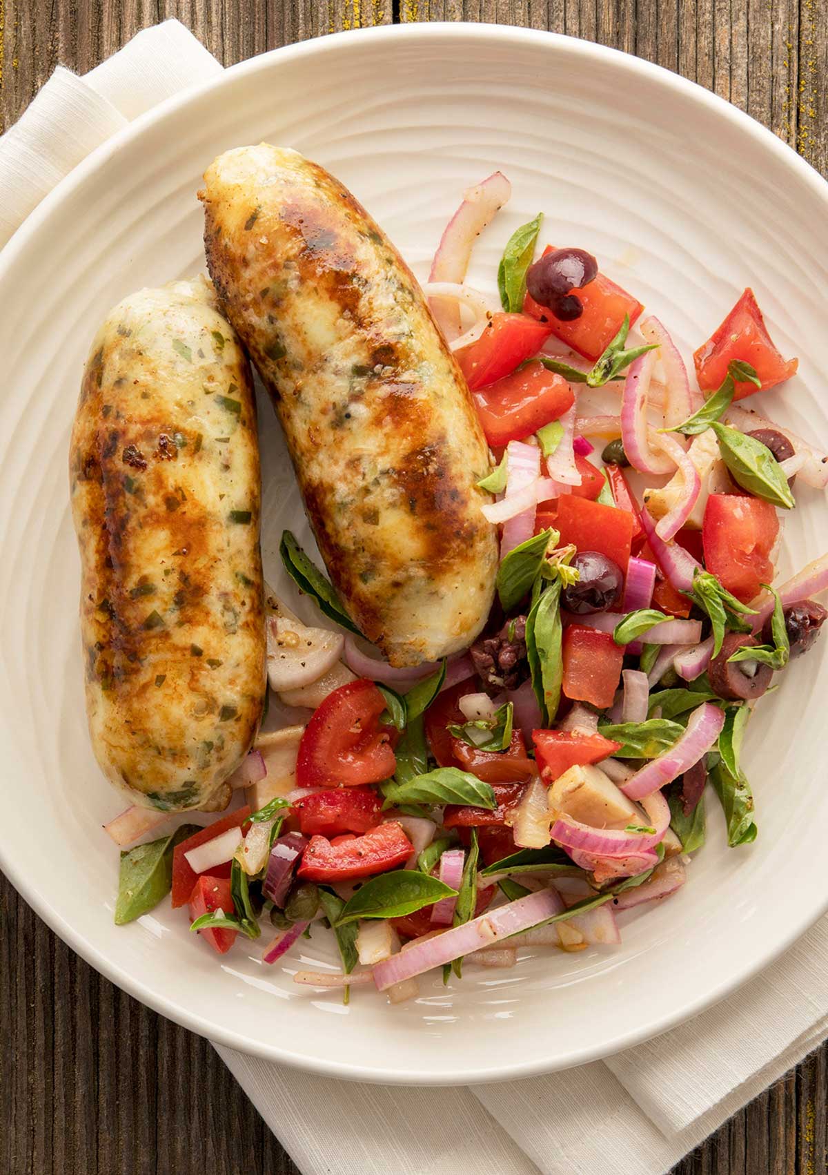 Grilled fish sausage on a plate with a summer salad. 