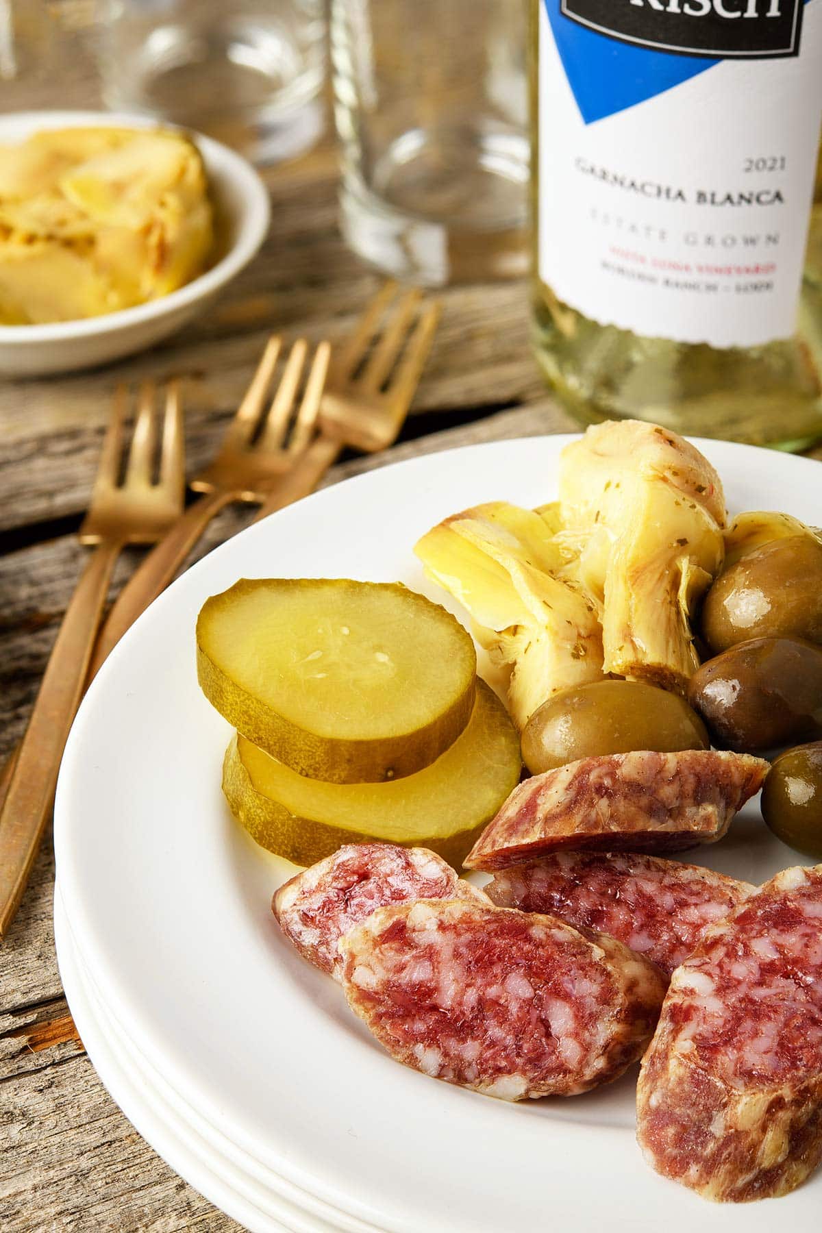 Close-up of slices of fuet sausage on a plate with pickles. 