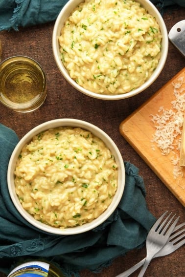 Two bowls of garlic parmesan risotto with white wine alongside.