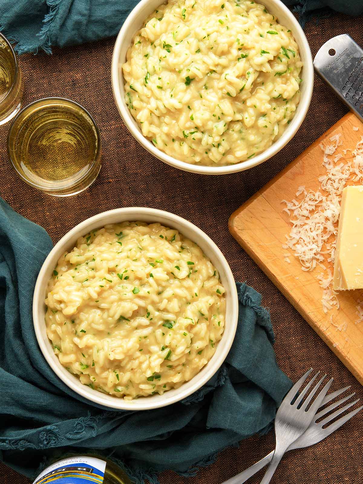 Two bowls of garlic parmesan risotto with white wine alongside.