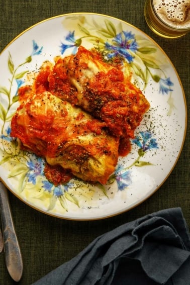 Two golumpki, Polish cabbage rolls, on a plate with tomato sauce.
