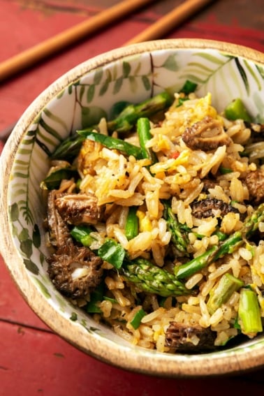Close up of a bowl of mushroom fried rice with morels and asparagus.