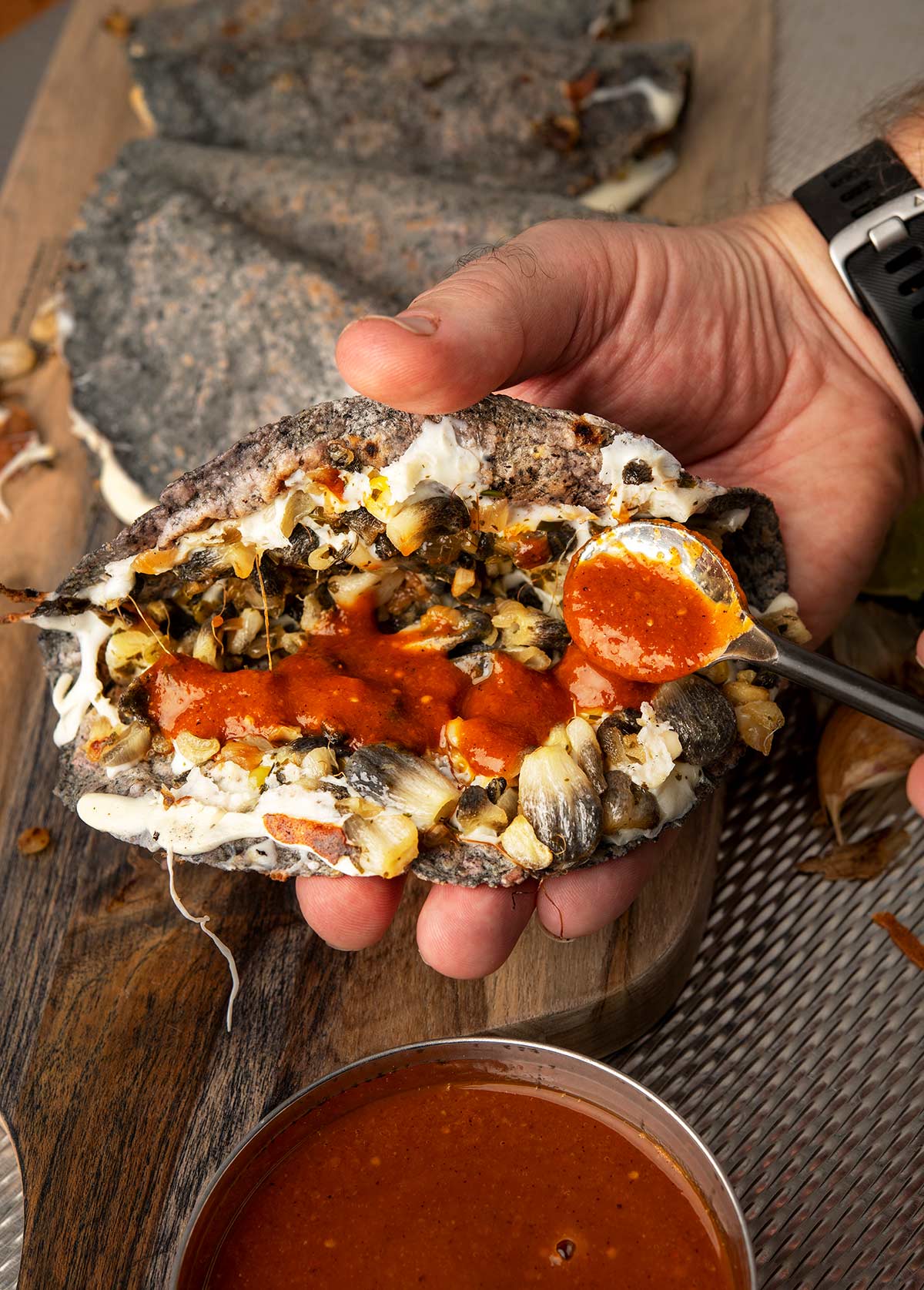 Adding salsa to a huitlacoche quesadilla.