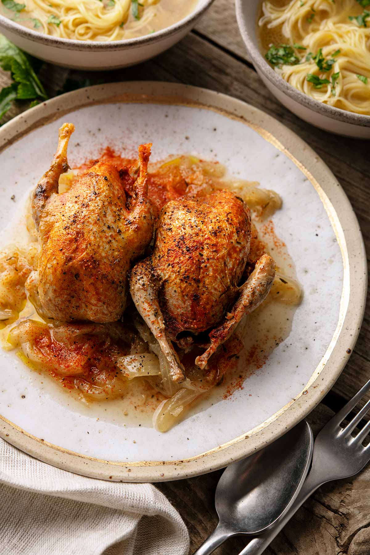 Two Spanish quail, stewed with onions, on a plate. 