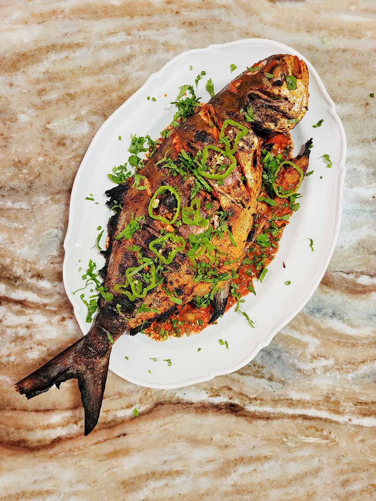 A grilled pompano on a plate. 