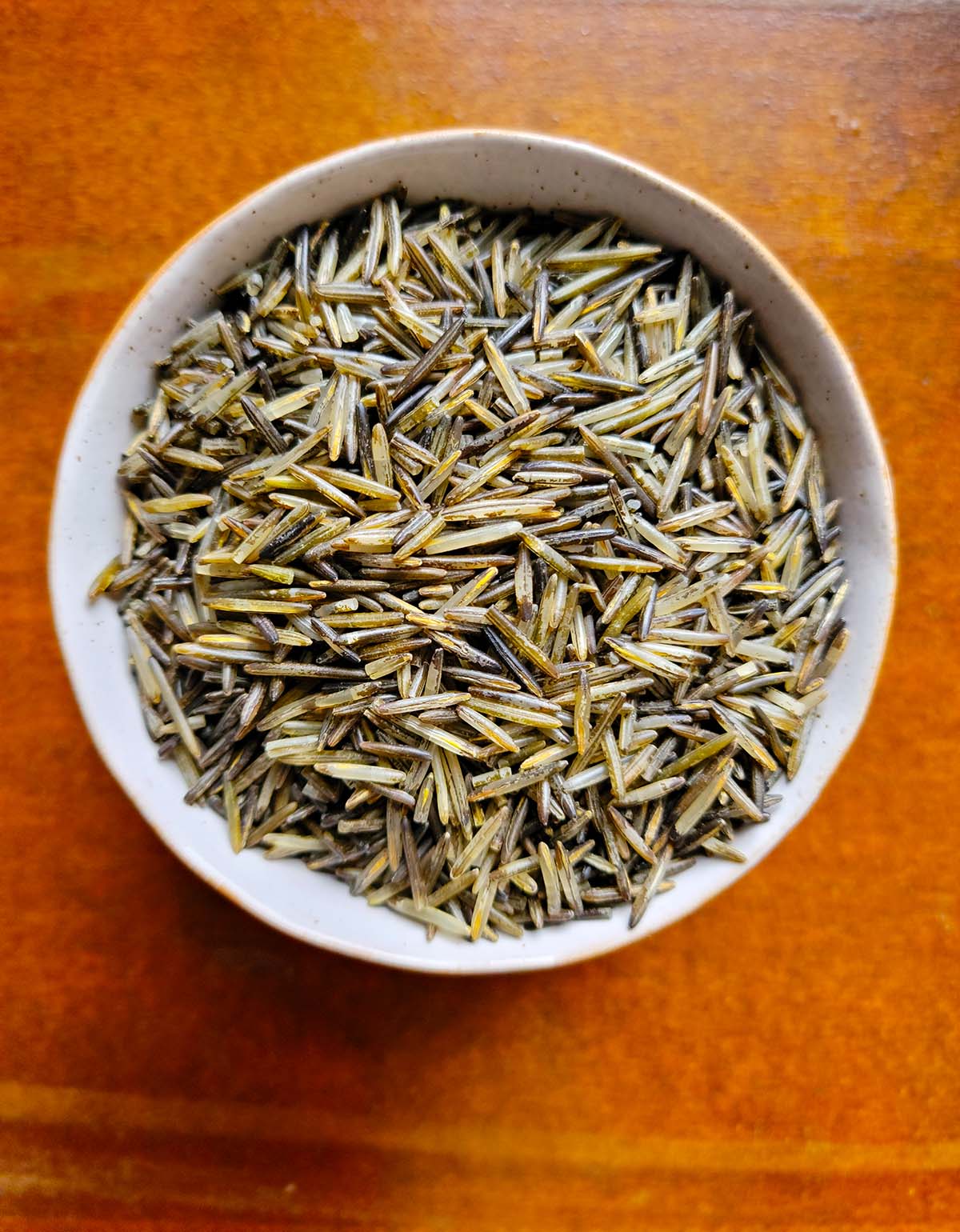 A bowl of uncooked, wild harvested, wood parched wild rice. 