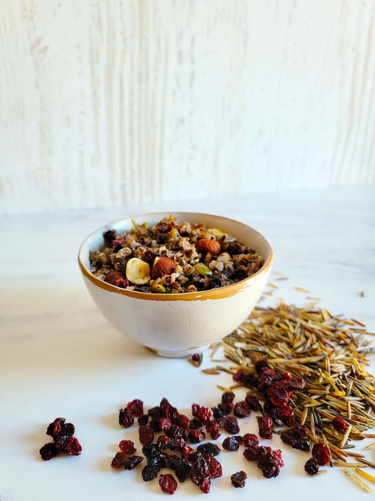 Wild rice porridge with uncooked wild rice and dried lingonberries alongside. 