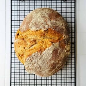 A light rye bread cooling on a rack.