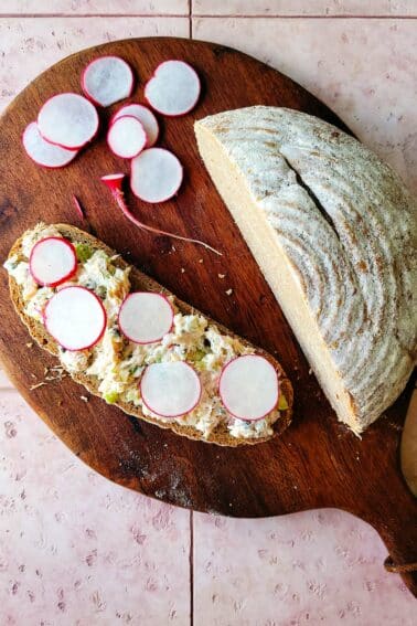 A platter with sliced radishes, rye bread and smoked witefish salad.