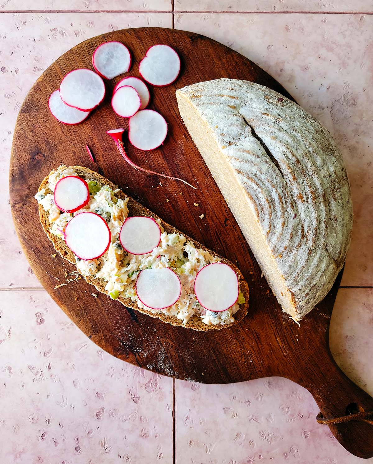 A platter with sliced radishes, rye bread and smoked witefish salad.