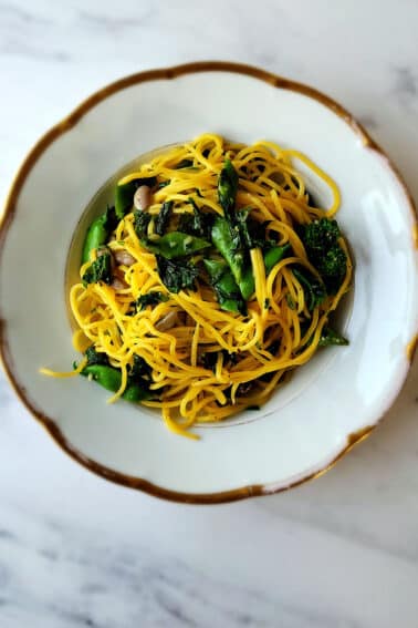 A bowl of tajarin pasta with beans and greens.