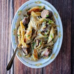 A platter of shupfnudeln, German dumplings, with sausages, onions and sauerkraut.