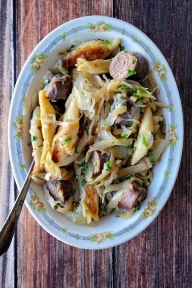 A platter of shupfnudeln, German dumplings, with sausages, onions and sauerkraut.