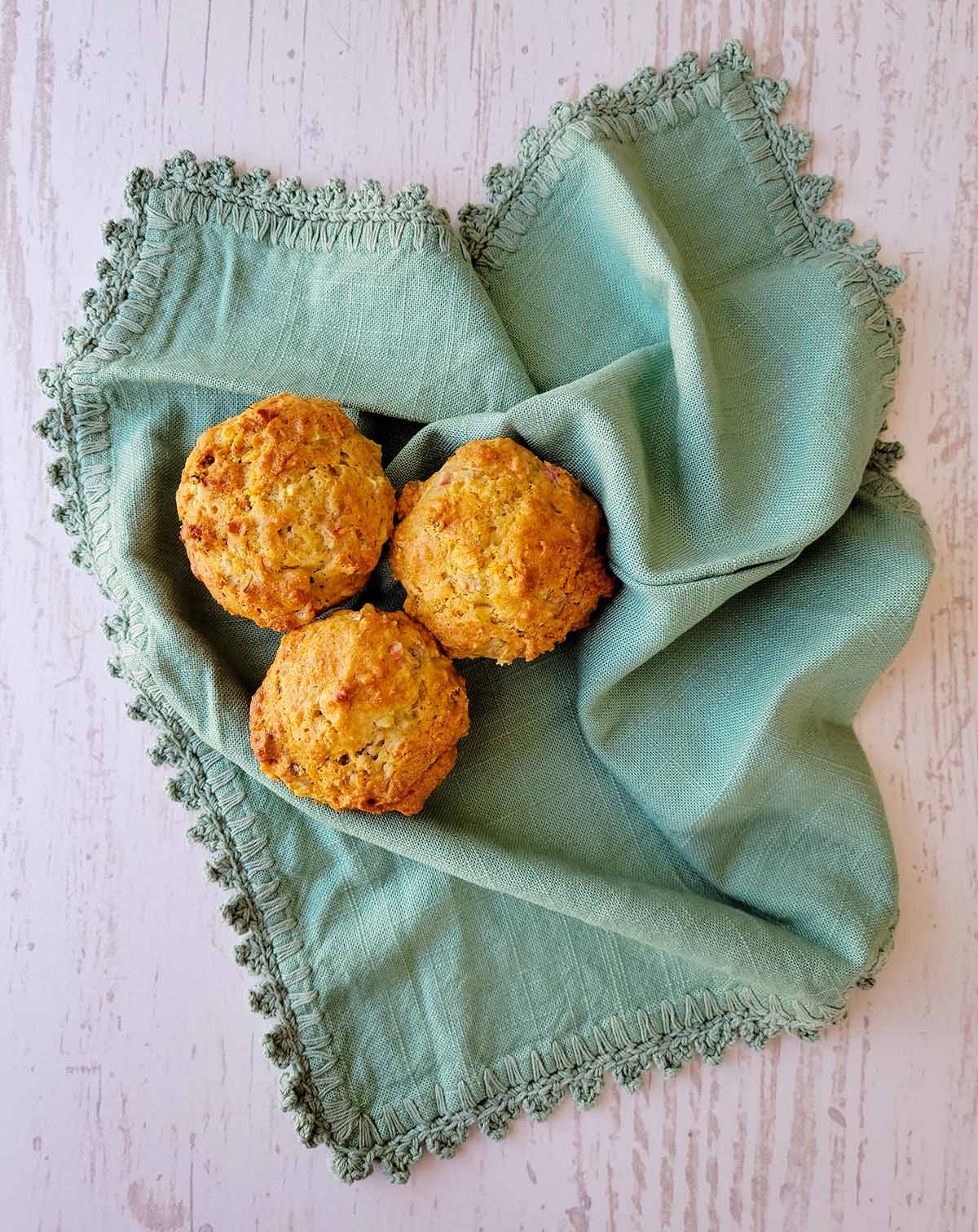 Three rhubarb muffins on a tea towel.