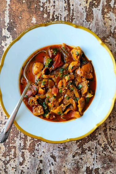 A bowl of mushroom stew on a wooden table.
