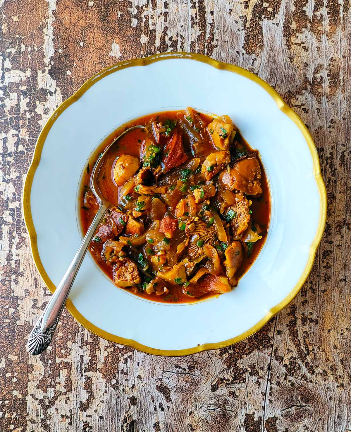 A bowl of mushroom stew on a wooden table. 